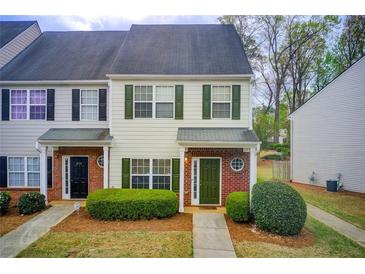 Charming townhome with manicured bushes, neutral siding, green shutters and door, and brick accents at 2758 Snapfinger Mnr, Decatur, GA 30035