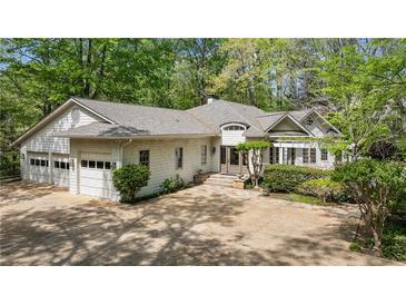 Charming home with a two-car garage, well-manicured landscaping, and a welcoming facade with mature trees at 5251 Powers Ferry Rd, Atlanta, GA 30327