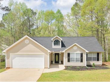 Charming single-story home features a manicured lawn, attached garage, and inviting front entrance at 135 Kimbell Farm Dr, Locust Grove, GA 30248