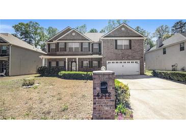 Charming two-story brick home featuring a front porch, attached garage, and a well-manicured lawn at 4312 Defoors Farm Trl, Powder Springs, GA 30127