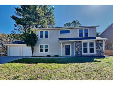Charming two-story home with stone accents, a well-manicured lawn, and an attached two-car garage at 955 Laurel Mill Dr, Roswell, GA 30076