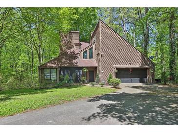 A charming two-story house with a wood exterior is surrounded by lush green trees at 2451 Cedar Fork Trl, Marietta, GA 30062