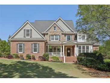 Stunning brick two-story home featuring manicured lawn, lush landscaping, and a welcoming front porch at 403 Grassmeade Way, Snellville, GA 30078