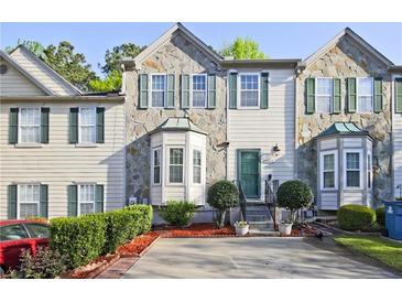 Charming townhome featuring stone accents, a well-manicured lawn, and a private driveway at 2557 Summit Cove Dr # 128, Duluth, GA 30097