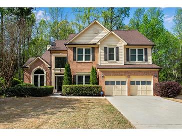 Charming two-story brick home with a well-manicured lawn and an attached two-car garage at 3665 Evonvale Gln, Cumming, GA 30041