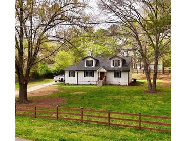 Charming two-story home featuring white siding, dormer windows, and a well-maintained front yard at 2638 Cleburne Pkwy, Powder Springs, GA 30127