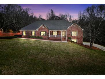 Charming brick home featuring a manicured lawn, covered porch, and inviting curb appeal at twilight at 503 Clearwater Dr, Mcdonough, GA 30252