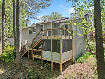 Spacious backyard featuring a screened porch and wooden deck surrounded by mature trees, perfect for outdoor enjoyment at 1842 Jarrett Dr, Lawrenceville, GA 30043