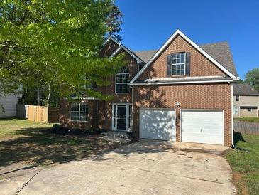 Charming two-story brick home featuring an attached two-car garage and a well-maintained lawn at 5719 Star Flower Dr, Ellenwood, GA 30294
