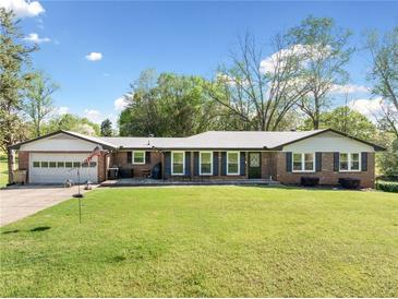 Ranch home featuring a lush green lawn and inviting curb appeal with a charming brick exterior and an attached garage at 630 Cambridge Dr, Marietta, GA 30066