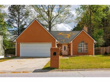 Charming one-story brick home featuring an attached garage, well-maintained lawn, and inviting front entrance at 1960 Banks Way, Atlanta, GA 30349
