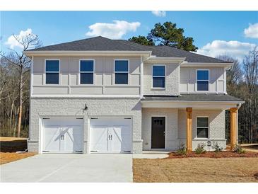 Two-story home featuring a white brick facade, a two-car garage, and a covered front porch with natural wood pillars at 342 Overlook Rd, Covington, GA 30014