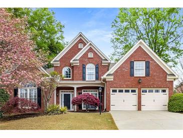 Charming two-story brick home featuring a manicured lawn, mature landscaping, and a two-car garage at 1442 Valley Glen Way, Dunwoody, GA 30338