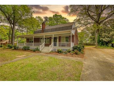 Charming brick home featuring a welcoming front porch, a well-manicured lawn, and an inviting facade at 177 Fairview Dr, Fairburn, GA 30213