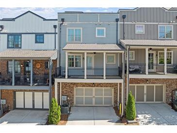 Townhome with gray siding, brick accents, and balcony with black railings above garage at 6135 Redwine St, Norcross, GA 30071