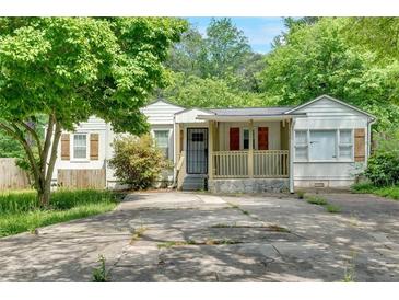 Lovely one-story home boasts a cozy front porch, stone accents, and a large driveway, nestled among mature trees and shrubs at 1728 Line St, Decatur, GA 30032