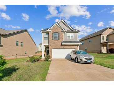 Charming two-story home features brick and siding, a well-maintained lawn, and an attached two-car garage at 2142 Theberton Trl, Locust Grove, GA 30248