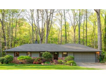 Charming single-story home featuring a brick facade, lush lawn, and mature trees, with an attached garage at 1850 Winchester Trl, Brookhaven, GA 30341
