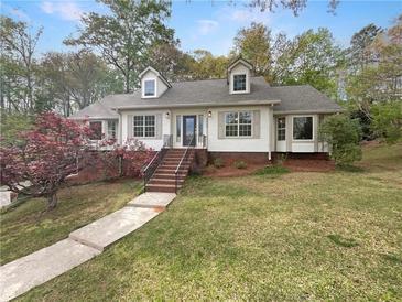 Charming home with manicured lawn, blooming tree, and inviting staircase leading to the front door at 8608 Creekview Ct, Douglasville, GA 30135