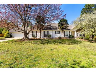 Charming one story home with a well-manicured lawn, mature trees, and inviting curb appeal at 65 Woodside Ct, Mcdonough, GA 30253