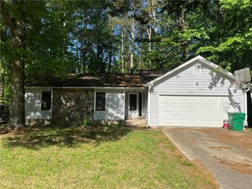 Charming single-story home with a stone facade, attached garage, and lush green lawn at 1228 Reilly Ln, Clarkston, GA 30021