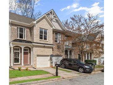 Charming townhome showcasing a brick and stone exterior, attached garage, and manicured front yard at 4866 Pinnacle Dr, Stone Mountain, GA 30088