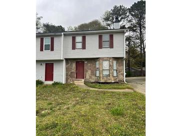 Two-story townhome with stone facade and red doors, nestled in a residential neighborhood at 3604 Hopkins Ct, Powder Springs, GA 30127