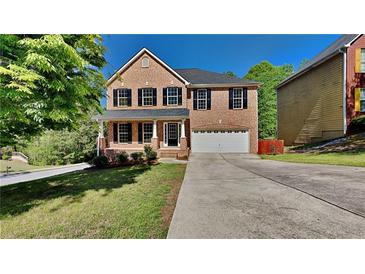 Charming two-story brick home featuring a covered porch, well-maintained lawn, and a long driveway leading to a two-car garage at 609 Millstone Dr, Jonesboro, GA 30238