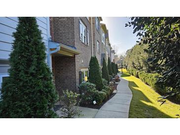 Charming brick townhome featuring a sidewalk surrounded by manicured landscaping and lush greenery at 3084 Turman Cir, Decatur, GA 30033