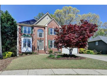 Charming two-story brick home with a well-manicured lawn and mature landscaping at 320 Hillside Manor Dr, Sugar Hill, GA 30518