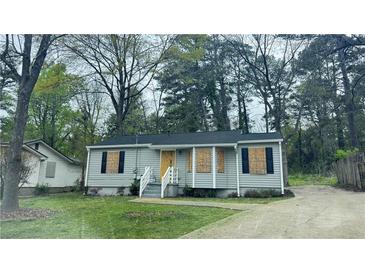 Quaint bungalow-style home with boarded windows, a concrete driveway, and verdant trees surrounding the property at 4262 Lindsey Dr, Decatur, GA 30035