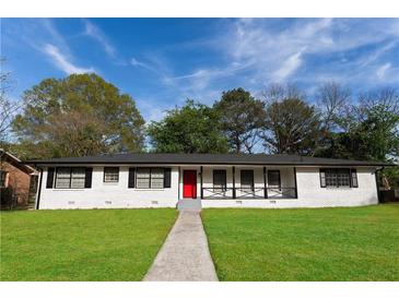 Charming single-story home with a red door, manicured lawn and a welcoming front porch at 3036 Crabapple Cir, Decatur, GA 30034
