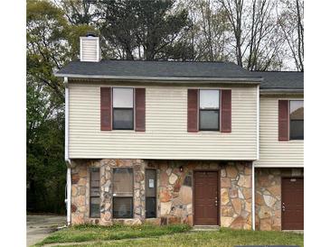 Two story townhouse featuring a stone facade, vinyl siding, and complementary dark brown shutters at 3628 Hopkins Ct, Powder Springs, GA 30127