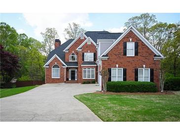 Traditional brick home with manicured lawn, dark shutters, and a large driveway, offering classic curb appeal at 2165 Sugarstone Ct, Lawrenceville, GA 30043
