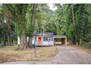 Charming single-story home with covered parking and a welcoming orange front door nestled among mature trees at 2437 Clarissa Nw Dr, Atlanta, GA 30318