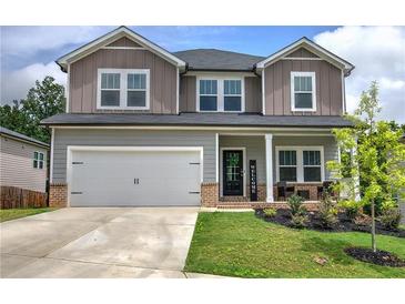 Charming two-story home featuring a two car garage and a welcoming front porch, set against a bright, cloudy sky at 419 Murphy Ave, Canton, GA 30114