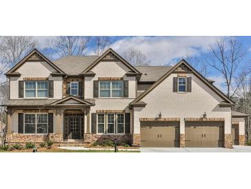 Charming two-story home with a brick and stone facade, complemented by a two-car garage and mature trees at 4585 Woodland Bank Blvd, Buford, GA 30518