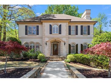 Elegant two-story home featuring a manicured front yard and a stone walkway leading to the arched front door at 9860 Hunt Club Way, Johns Creek, GA 30022
