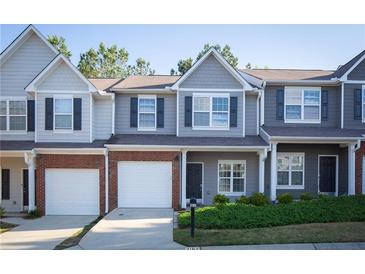 Charming townhome featuring a gray exterior, brick accents, attached garage, and well-maintained landscaping at 2162 Spikerush Way, Buford, GA 30519