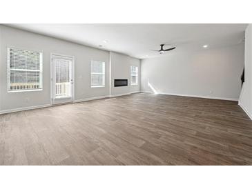 Bright, open-concept living room with hardwood floors, a fireplace, and ample natural light from large windows at 358 Orwell Dr, Social Circle, GA 30025