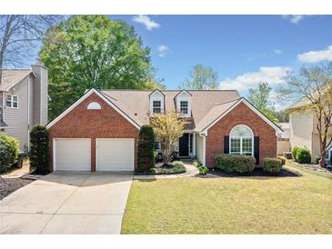 Charming brick home with a well-manicured lawn, mature trees, and an attached two-car garage at 1483 Chamirey Sw Dr, Marietta, GA 30008