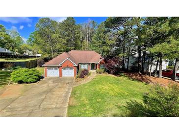 Charming brick home featuring a two-car garage, lush lawn, and mature trees at 223 Cheatham Rd, Acworth, GA 30101