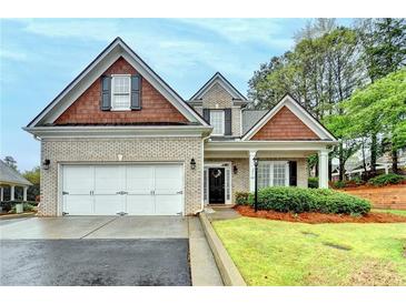 Charming two-story brick home with a well-manicured lawn and attached two-car garage on a sunny day at 2920 Olde Towne Pkwy, Duluth, GA 30097
