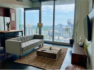 Bright living room featuring a modern sofa, wood accents, and large windows with scenic city views at 860 Peachtree Ne St # 2616, Atlanta, GA 30308