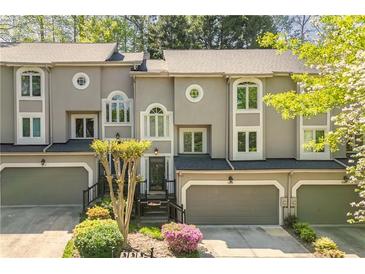 Charming townhome featuring a garage, front garden, and gray stucco exterior at 1209 Brookhaven Woods Ne Ct, Brookhaven, GA 30319