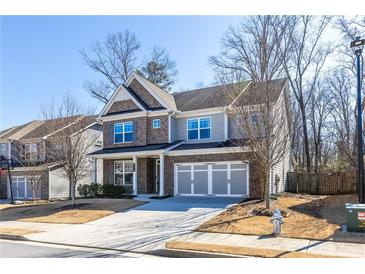 Charming two-story home featuring a brick and gray exterior, attached garage, and a well-manicured front lawn at 333 Gardens Of Harmony Dr, Canton, GA 30115