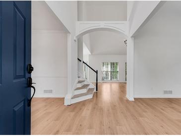 Inviting foyer featuring soaring ceilings, staircase, wood floors, and an abundance of natural light at 4414 Aldenham Way, Suwanee, GA 30024