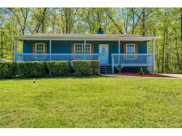 Charming blue house featuring a cozy front porch, complemented by a well-maintained, lush green lawn and mature trees at 166 Rustin Dr, Dallas, GA 30157