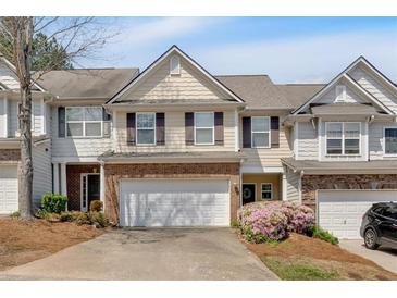Charming townhome featuring a two-car garage and well-manicured landscaping at 706 Woodland Pl, Woodstock, GA 30188