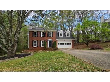 Charming two-story brick home featuring a well-manicured lawn, attached garage, and mature trees at 1200 Izod Ct, Lawrenceville, GA 30044
